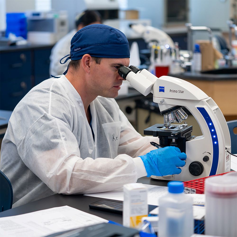 An MLT student working with a microscope.