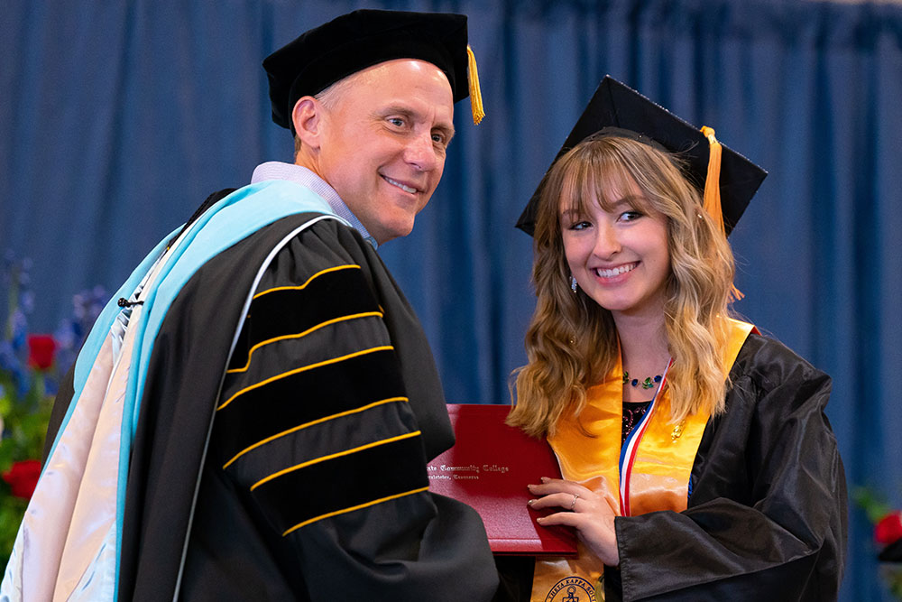 Dr. Tony Miksa hands a graduate her degree.